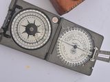 a compass and a leather case on a white surface