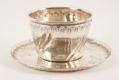 une tasse et une soucoupe en argent posées sur une soucoupe
