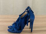 blue high heeled shoes with fringes on a wooden surface