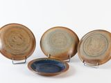 three brown and blue plates sitting next to each other on a white surface