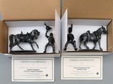 two black figurines of a man on a horse and a man on a horse in a box