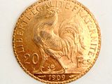 a gold coin with a rooster on it on a white surface