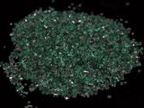 close up of a pile of green crushed glass on a black surface