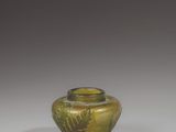 a green glass vase with a design on the lid