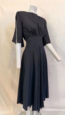 black dress on a mannequin stand against a white backdrop