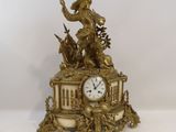 a gold clock with a statue of a man on top of it