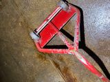 a red pipe cutter laying on the floor next to a toilet