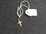 un petit collier avec une croix en or et une plaque accrochée dessus