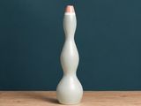 un vase blanc posé sur une table en bois, près d'un mur bleu