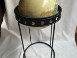 un vieux globe terrestre posé sur un socle, sur fond blanc
