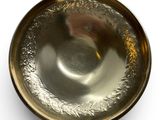 a silver bowl with a gold rim on a white surface