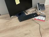 un bureau sur lequel se trouvent un écran, un clavier, un téléphone et d'autres objets