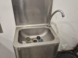 a stainless steel sink with a faucet in the corner of the room