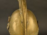 an antique helmet on a stand against a black background
