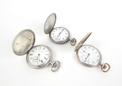 trois montres de poche en argent sont posées les unes à côté des autres sur une surface blanche