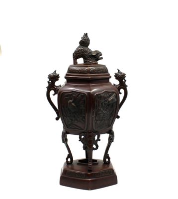 un grand vase marron surmonté d'un oiseau