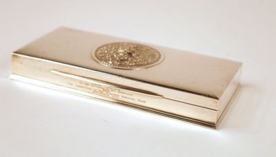 a silver business card case with a gold medallion on it