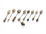 un ensemble de cuillères en argent et de cuillères à soupe posées sur une surface blanche