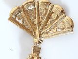 an image of a gold fan brooch on a white background