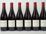 six bottles of red wine are lined up on a table