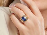 the woman is wearing a gold ring with a blue stone