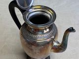 a silver tea pot with a lid and a spoon in it