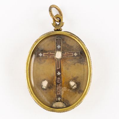 une image représentant un pendentif en forme de croix en or sur fond blanc