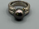 une bague ornée d'une perle noire, posée sur une table