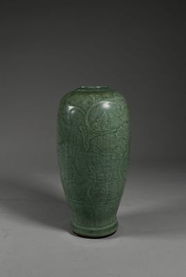 a green vase sitting on top of a table next to a gray wall