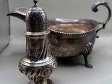 a silver salt and pepper shaker sitting next to a silver bowl