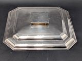 a silver plate with a lid on a black surface