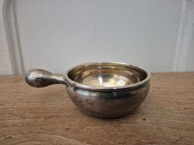 a small metal bowl with a spoon on a table