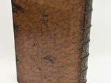 an old book with a brown cover sitting on top of a white surface