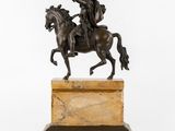 an antique bronze statue of a man on a horse holding a sword