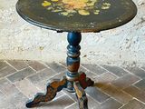 a small table with a painted top on a brick floor