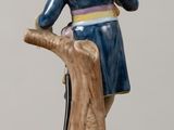 a figurine of a man sitting on a tree trunk