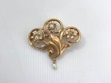 a close up of a gold brooch with pearls on it
