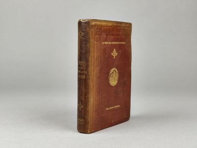 un livre marron orné d'un emblème doré, posé sur une surface blanche