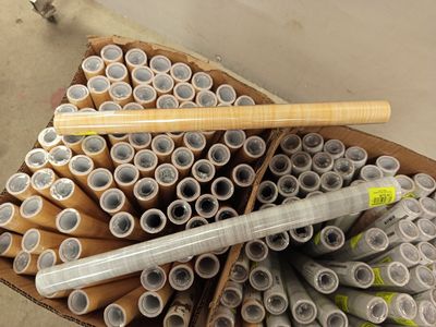 plusieurs rouleaux de papier toilette et une batte de baseball dans une boîte en carton
