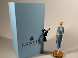 a small figurine of a woman standing next to a blue box