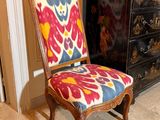 fauteuil rembourré aux couleurs vives placé devant une commode dans un salon
