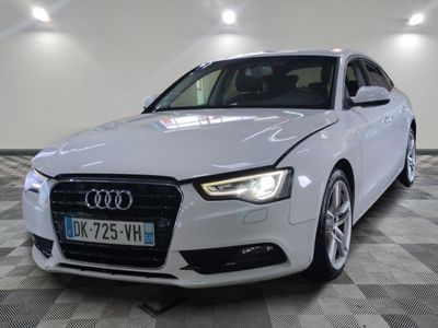 L'Audi blanche est garée dans une grande pièce au sol carrelé.