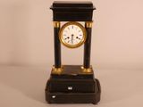 a black and gold clock on a stand on a white background