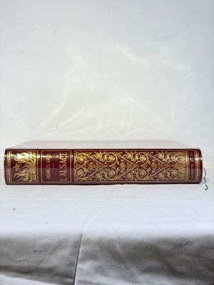 un livre rouge et doré posé sur une table blanche
