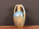 a blue and yellow vase sitting on a wooden table