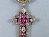 un gros plan d'une croix ornée d'une pierre verte et rose