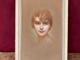 Un tableau représentant le visage d'une femme est présenté dans un cadre blanc.