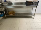 une table en acier inoxydable sur laquelle est posé un panier, dans une cuisine