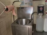 un évier dans un coin d'une cuisine où s'entassent de nombreuses bouteilles