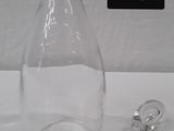 a clear glass bottle with a stopper next to it